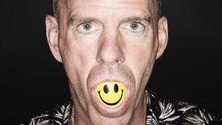 Photo of Fatboy Slim with a yellow smiley face ball in his mouth