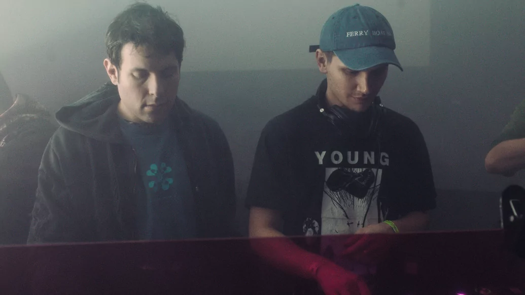 Photo of DJ Python and Nick Leon performing beneath hazy green lights at Strange Brew
