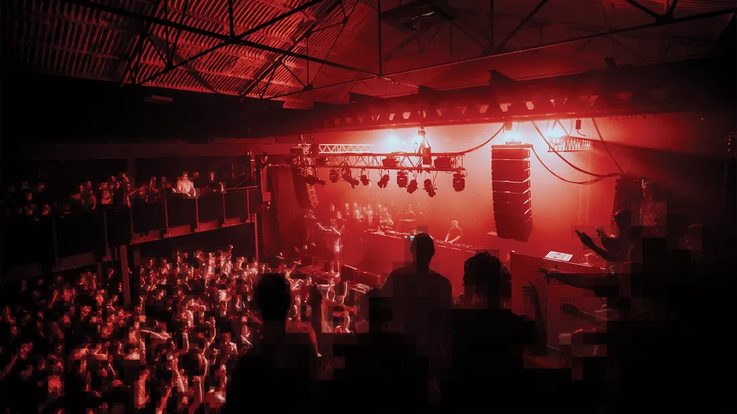a photo of Break performing in a club shot from a balcony under red lights