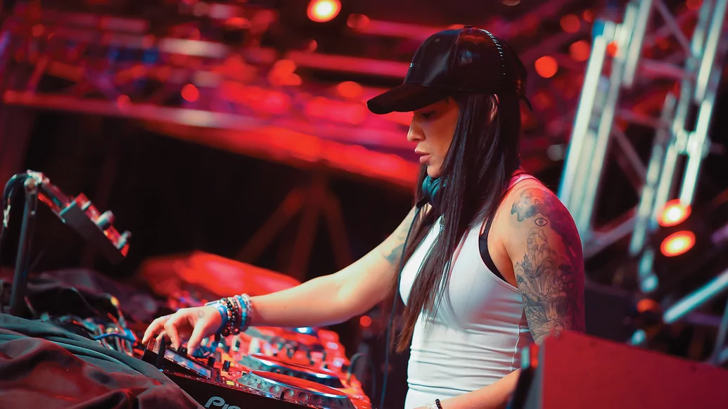 Photo of Fatima Hajji DJing while wearing a black cap