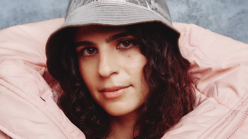Photo of Carlita posing wearing a grey bucket hat and light pink puffer