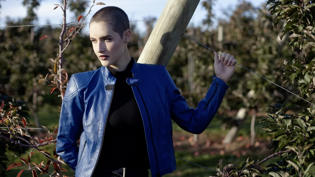 Photo of Madeline wearing a blue leather jacket and holding onto a wire