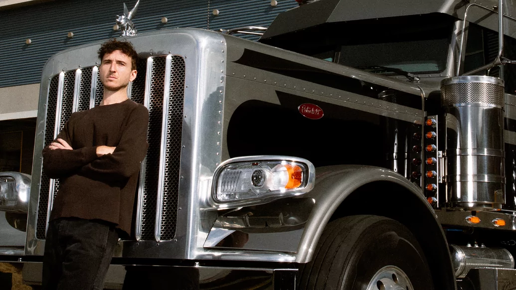 Photo of RL Grime wearing all black and standing in front of a truck