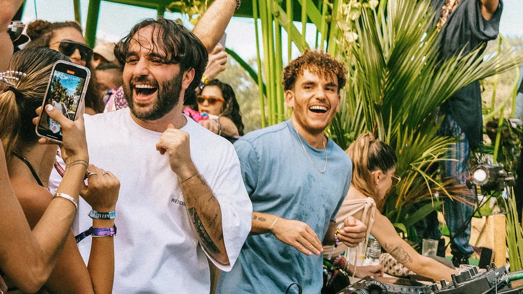 Photo of ANOTR DJing with a palm tree behind them
