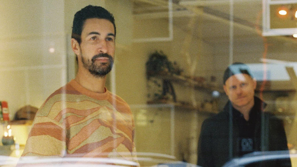 Photo of Frank & Tony through a glass pane looking into a yellow room