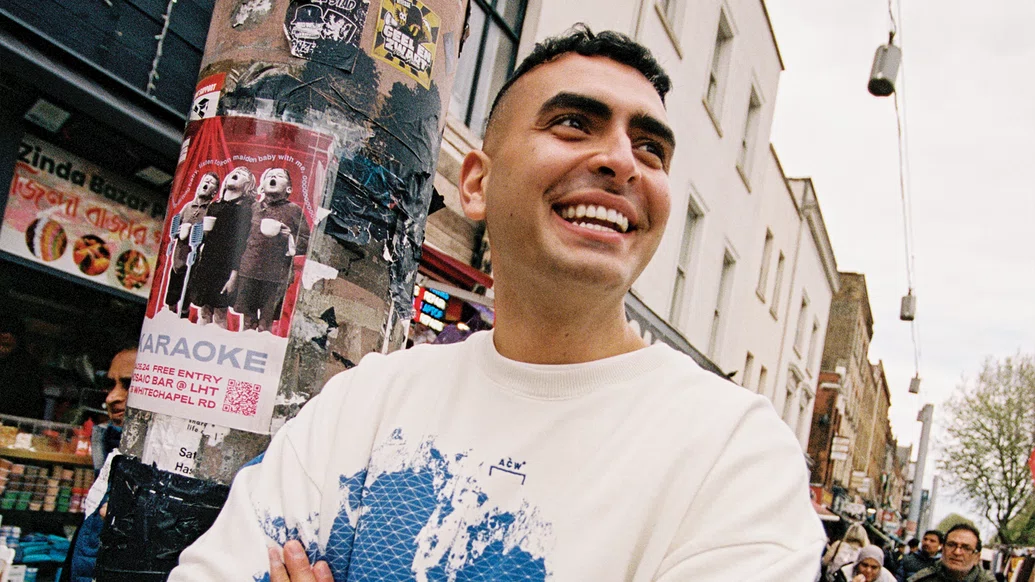 Photo of Sammy Virji grinning whilst walking through London