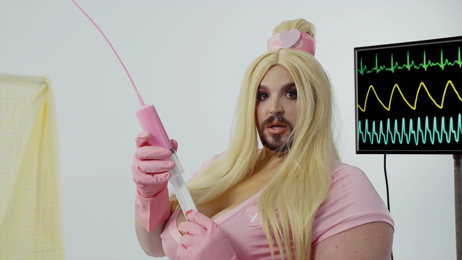 A still from Wreckno's EZ music video. They're dressed as a nurse in a pink costume holding a toy pink syringe