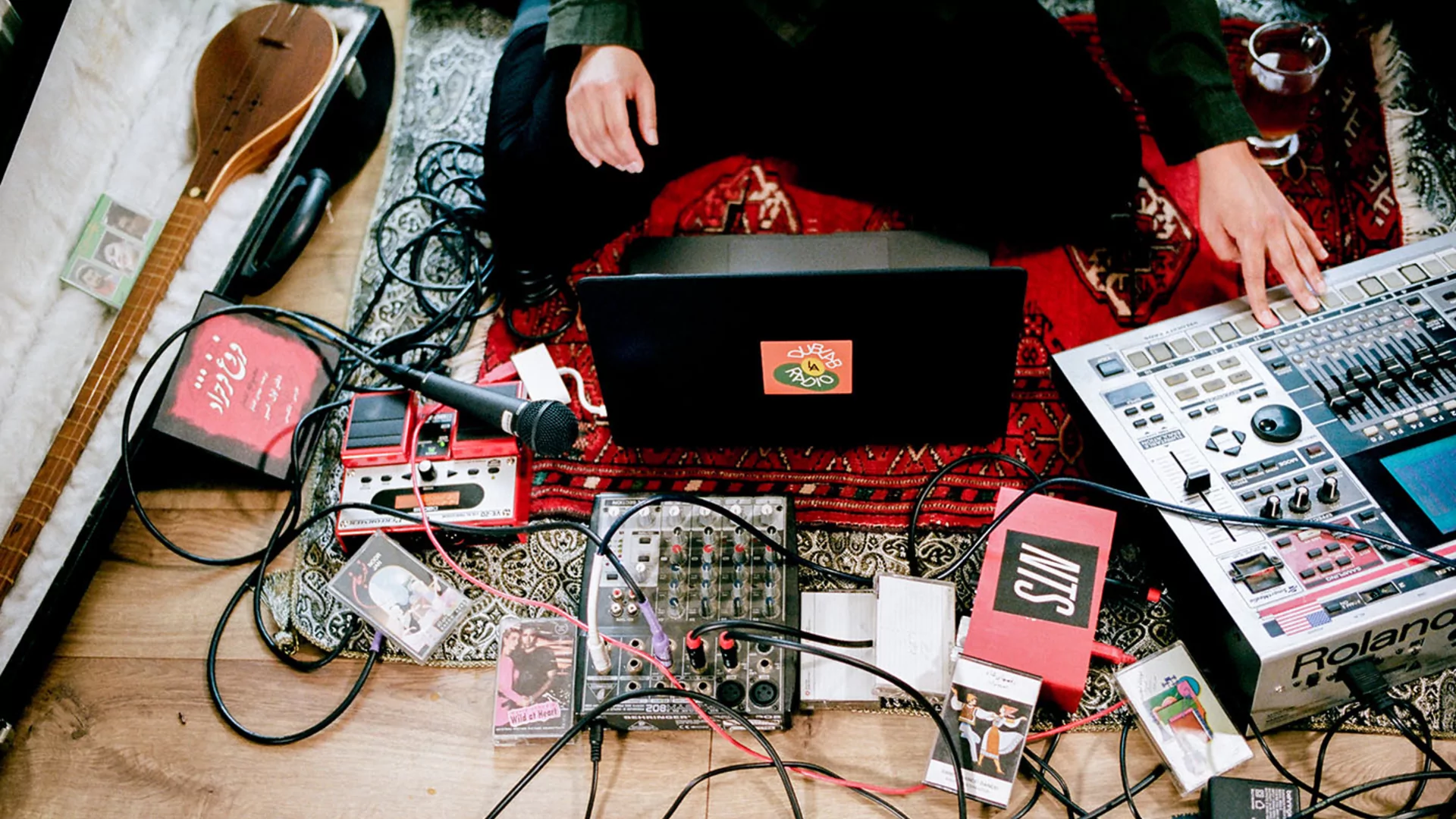 A photo looking down to Maral's laptop, sampler, pedals and cables on the floor