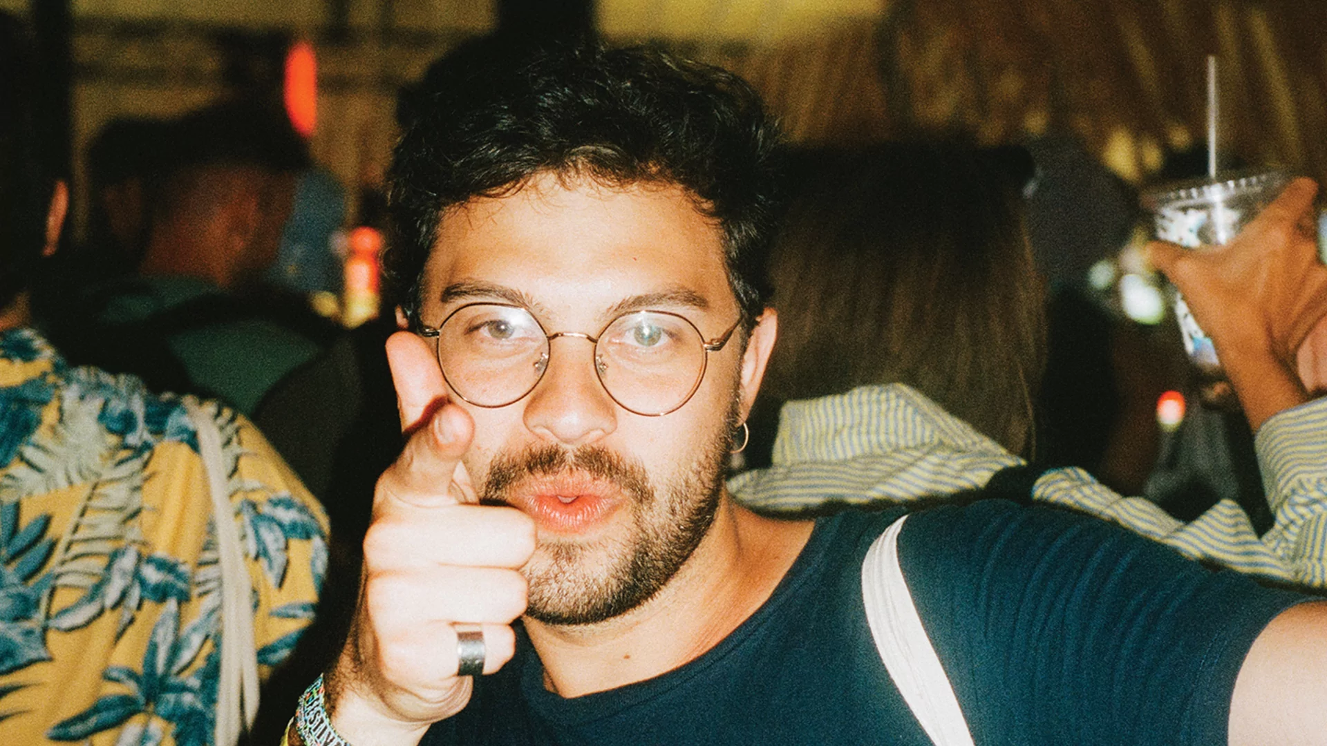 Nicolas Duque in glasses, dancing in a club will pointing at the camera