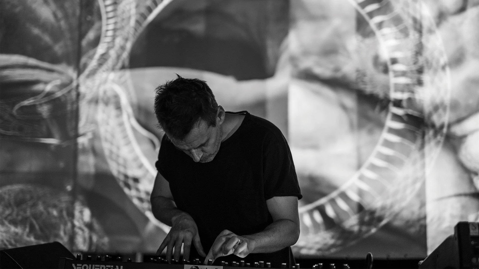 Photo of Clark DJing with a black and white spiral visual behind him