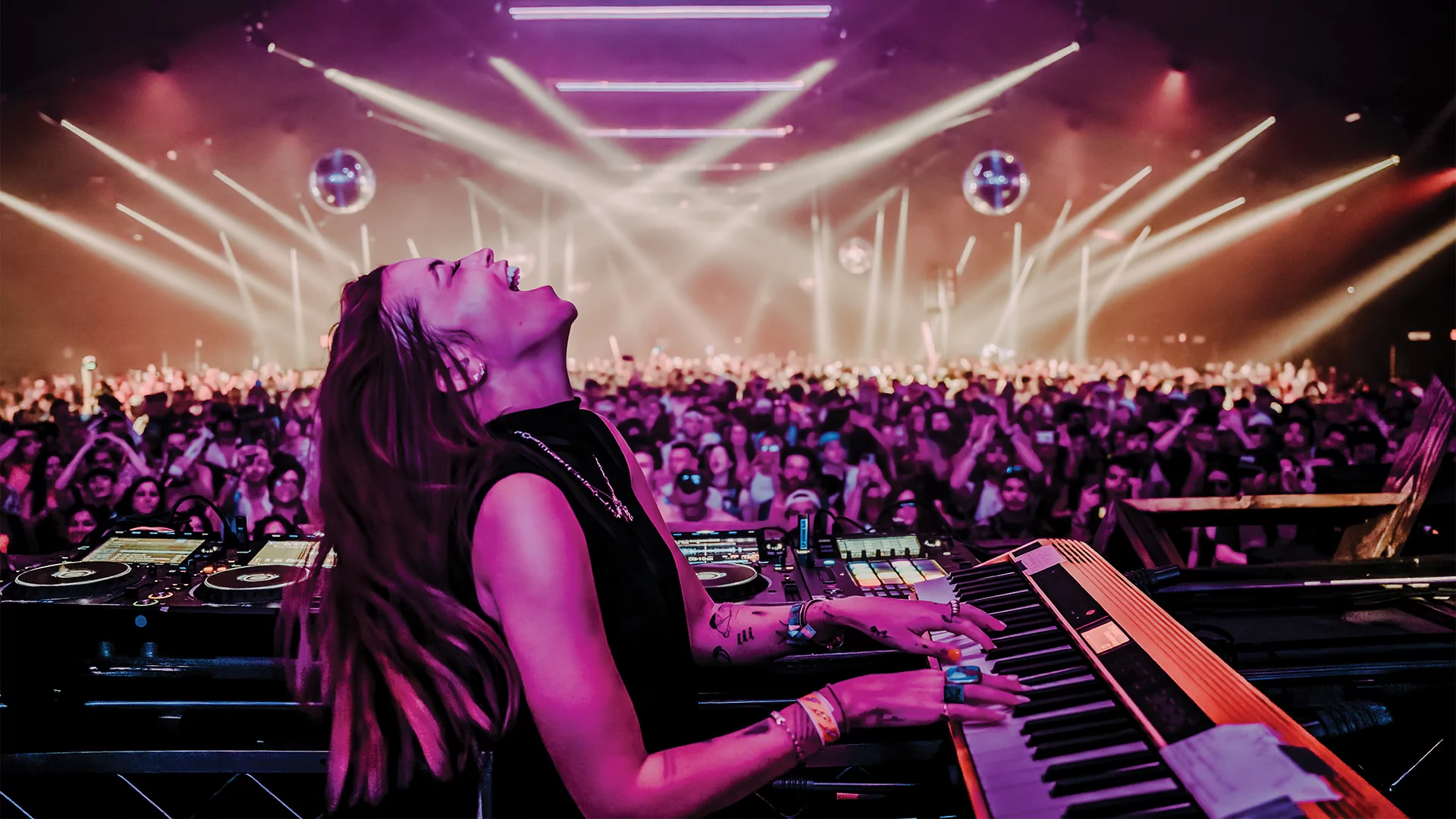 Photo of LP Giobbi throwing her head back while performing the piano on stage to a large crowd