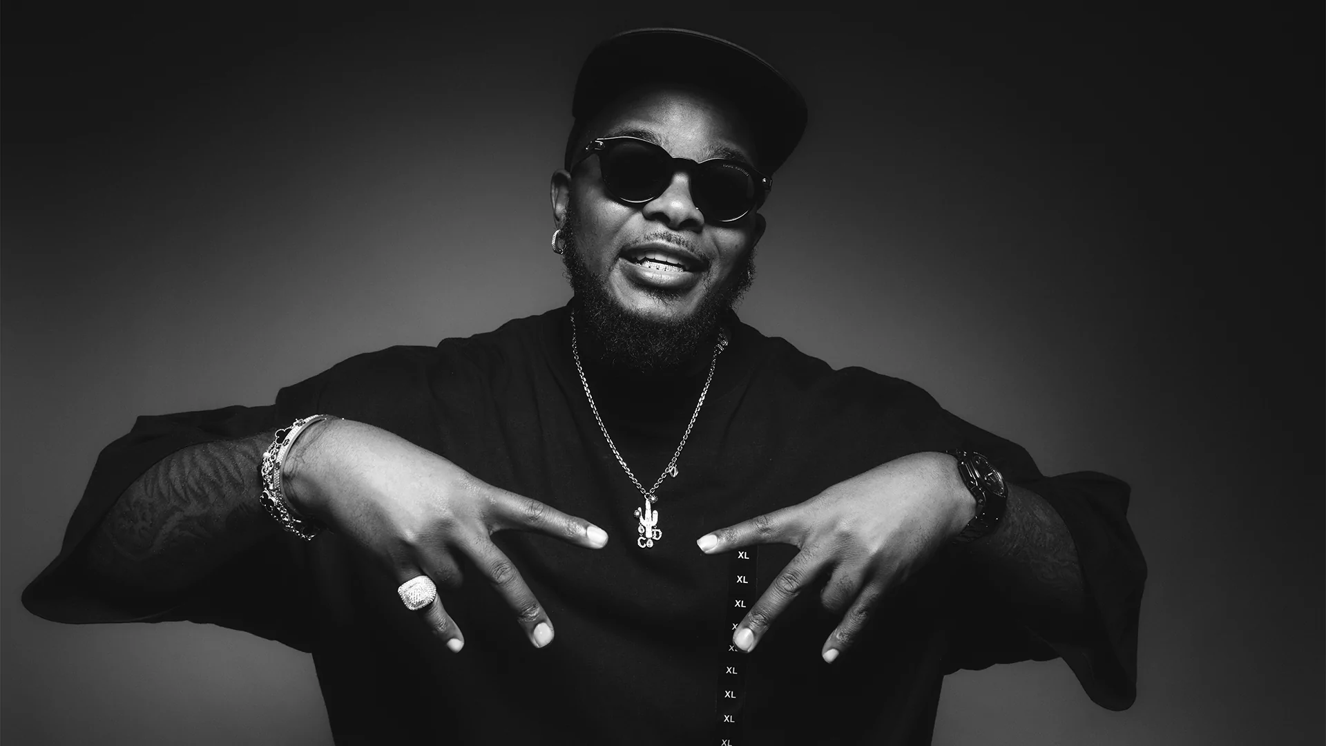 Black and white portrait of Bandile wearing grills, black sunglasses, and a chain