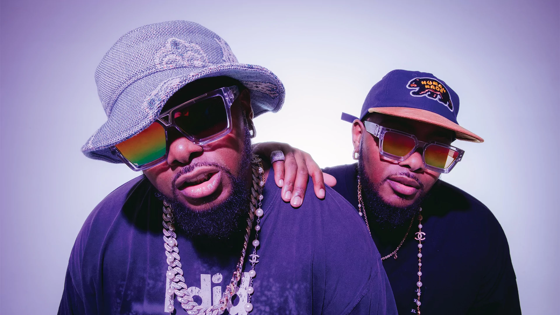 Photo of Bandile and Banele of Major League Djz wearing reflective sunglasses and hats in front of a white background
