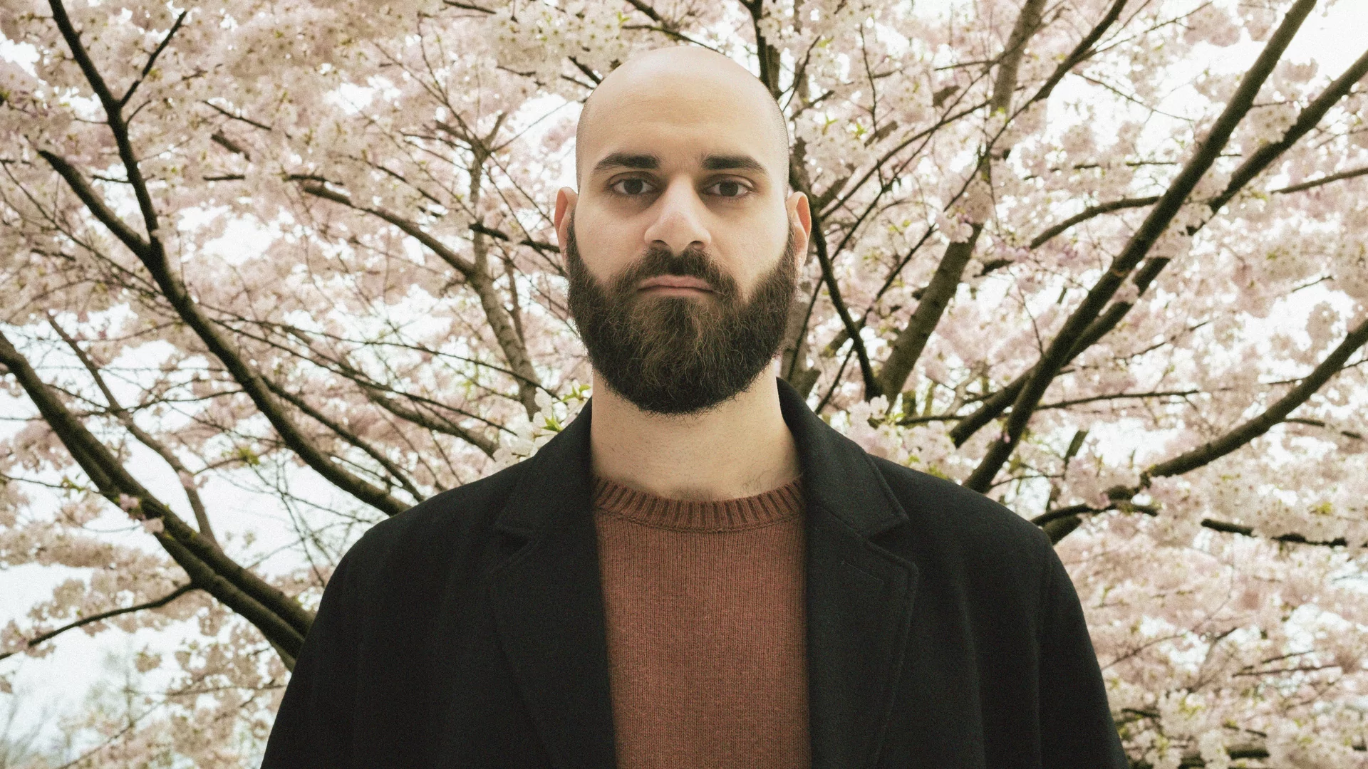 Photo of Omar Ahmad in front of a cherry blossom tree