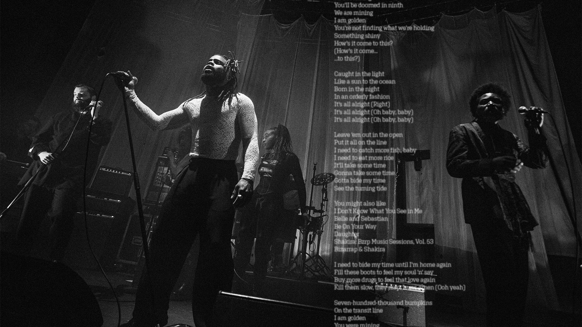 Photo of Young Fathers performing on stage in black and white with blurry lyrics