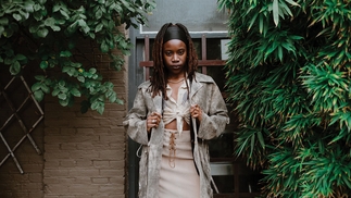 Gabrielle Kwarteng standing in front of a brick wall surrounded by green plants