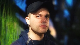 a hazy photo of Bungalovv in a black baseball cap against a blue and green background