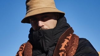 Photo of Stecher wearing a cream hat and scarf with a blue sky background