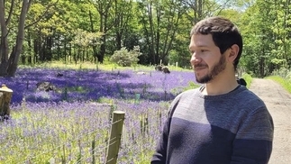 A photo of Conrad standing in front of a field of flowers