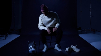SBTRKT sits on a chair looking down at trainers and an animal mask