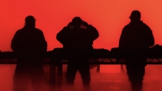 Photo of Swedish House Mafia outlined in shadows against a red background