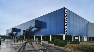 Photo of a vast blue warehouse with the word ‘DRUMSHEDS’ printed down the side of the building