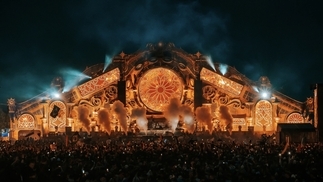 Photo of the main stage at Tomorrowland 2023 with flashing yellow lights and pyrotechnics 