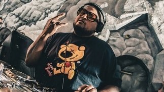 Photo of DJ Deeon behind the decks wearing sunglasses and a black bear shirt