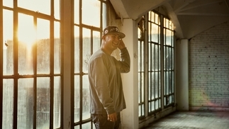 Photo of Avision standing in a warehouse space wearing a grey jumper and baseball cap