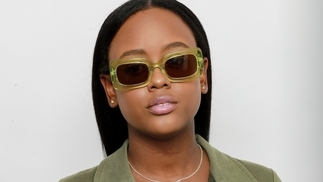 Photo of Dana Lu wearing a green blazer and matching green sunglasses against a white background
