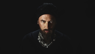 Photo of Damian Lazarus wearing all black and heavy silver jewellery while looking directly into the camera