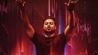 Photo of Quintino wearing a black t-shirt with his hands in the air