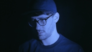 Photo of TSVI wearing a hat and glasses in a blue light