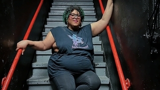 Photo of Lady Blacktronika sitting on some stairs with a red railing