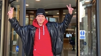 Photo of Michael Bibi holding up peace signs in front of the Royal Marsden hospital where he received treatment