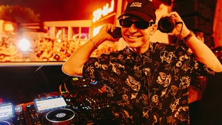 Photo of Michael Bibi behind the decks wearing a ‘Fuck Cancer’ hat