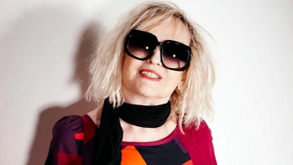 Photo of the late Annie Nightingale wearing big round sunglasses and a red patterned shirt