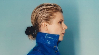 Photo of Robyn in profile looking right wearing a blue jacket with the collar up