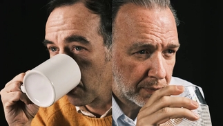 Photo of Soulwax brothers Stephen and David Dewaele drinking from mugs against a black background