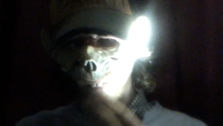 Photo of Ship Sket wearing an animal mask with a light flashing across his face
