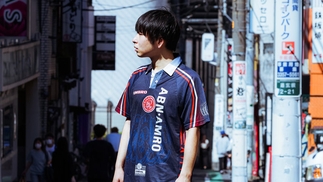 Seimei stands in the middle of a Tokyo street wearing a navy football jersey