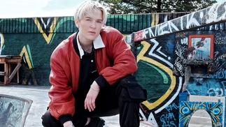 Ani Klang crouching in a skatepark wearing a red lather jacket