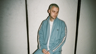 Photo of Blossom Hill wearing a denim tracksuit and sitting on a chair