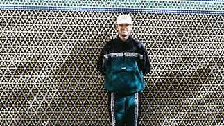 Photo of Gallegos wearing a navy and blue tracksuit against a tiled wall