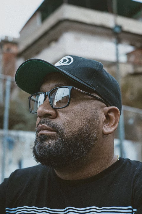 Close up of DJ Babatr looking to the left in a black baseball cap and sunglasses