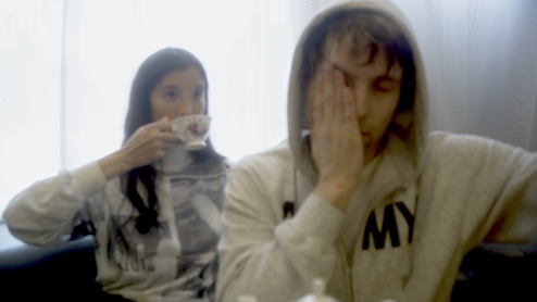 Photo of DJ Python touching his face and Ana Roxanne drinking from a mug.