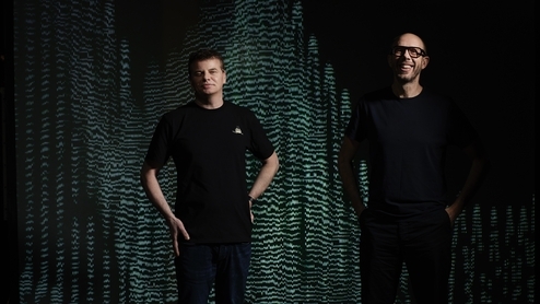 Photo of Tom Rowlands and Ed Simons from The Chemical Brothers smiling in front of a black and green electronic screen