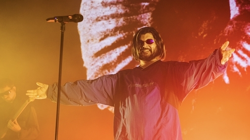 Photo of Jai Paul performing at Coachella wearing a parka coat and sunglasses