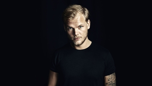 Photo of the late Avicii wearing a black t-shirt against a black background