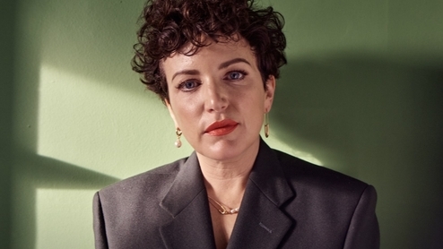 Photo of DJ Annie Mac wearing a grey suit and red lipstick